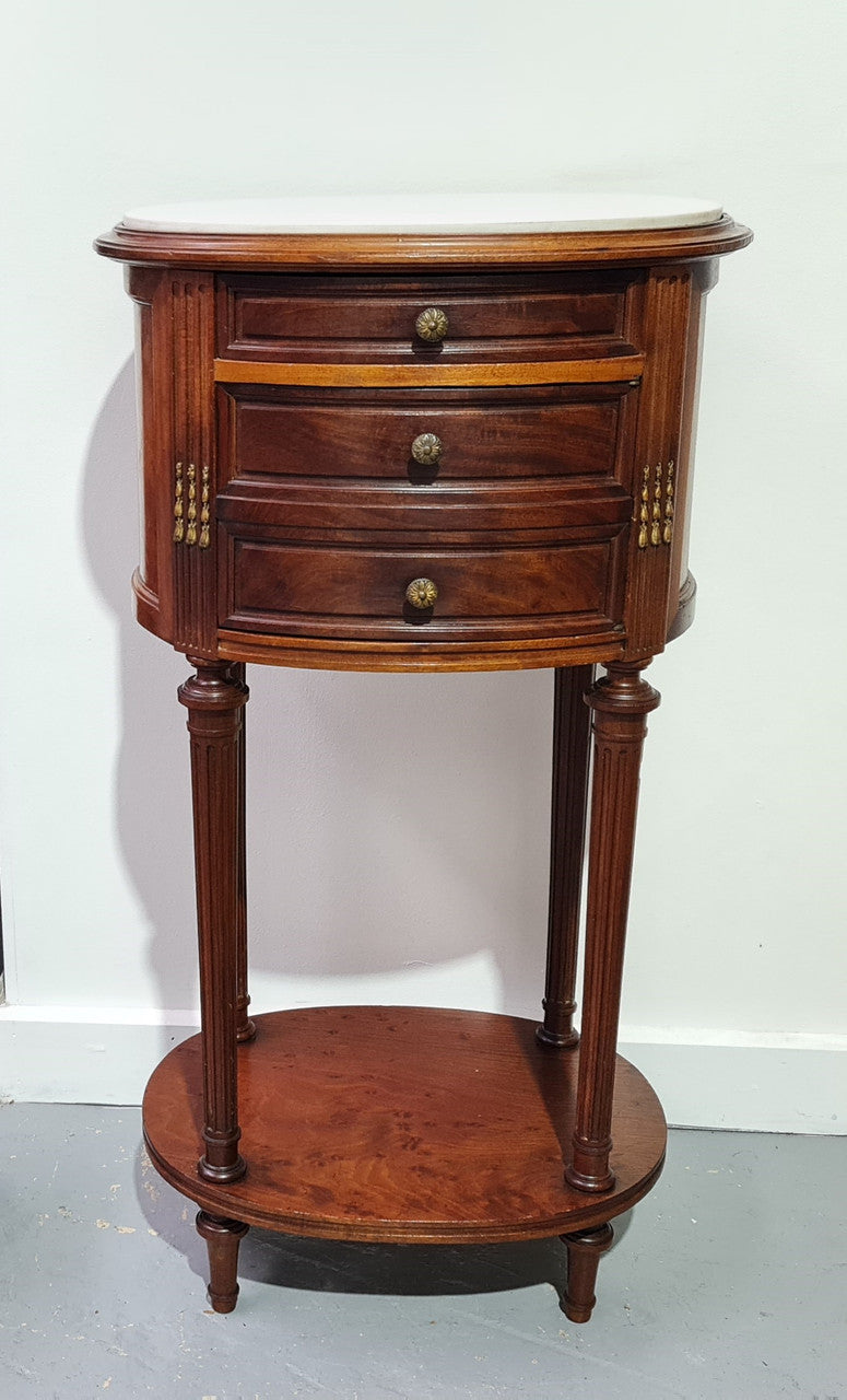 Round Louis XVI style Mahogany marble top side table. It has one drawer and a cupboard for storage. It is in good original detailed condition.