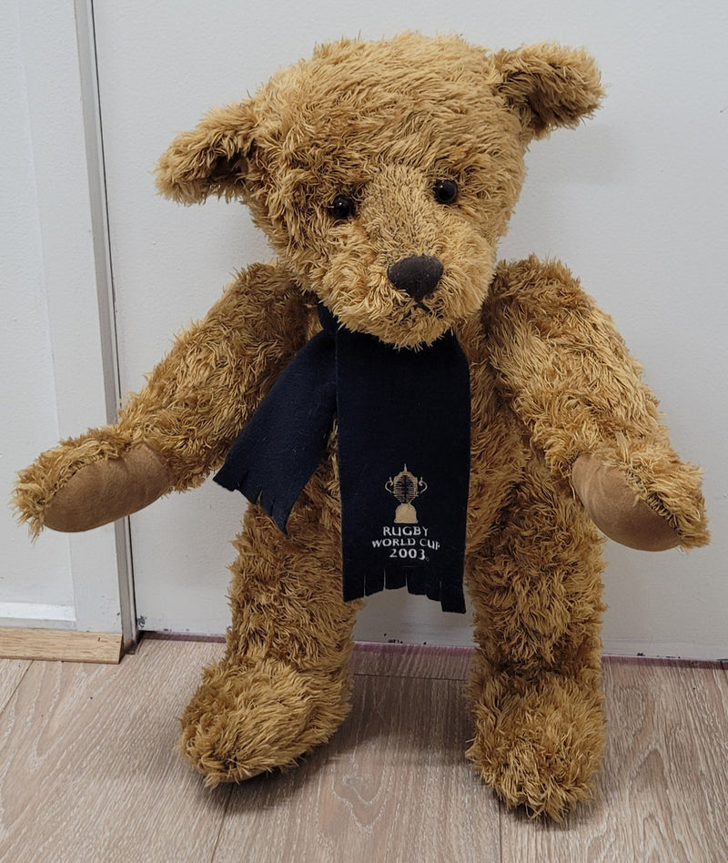 World Cup Rugby Bear. William by RUSS a special release for 2003. Limited to 5000 pieces worldwide. 50.8 cm fully jointed golden-brown bear with suedeen paw pads and blue scarf with Rugby World Cup Logo embroidery.

*Please note chair in photo is not included.