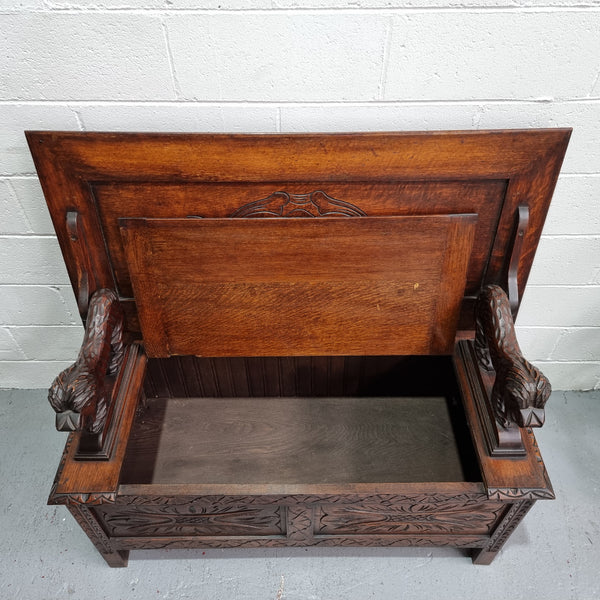 Unusual English Oak Monks Bench.  The tabletop is set onto a lift top chest in such a way that when the table is not in use, the top pivots to a vertical position and becomes the back of a Settle. Carved Lion table rests and carving to front.  In good, detailed condition.