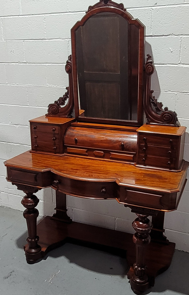 Beautiful Flame Mahogany Victorian duchess dressing table. Circa 1880 in date. It has a serpentine front outline and has an adjustable swing frame mirror. It is fitted with a central roll up storage section and then has three small drawers to either side, aswell as a central drawer in the middle of the serpentine front. It is in good original condition.