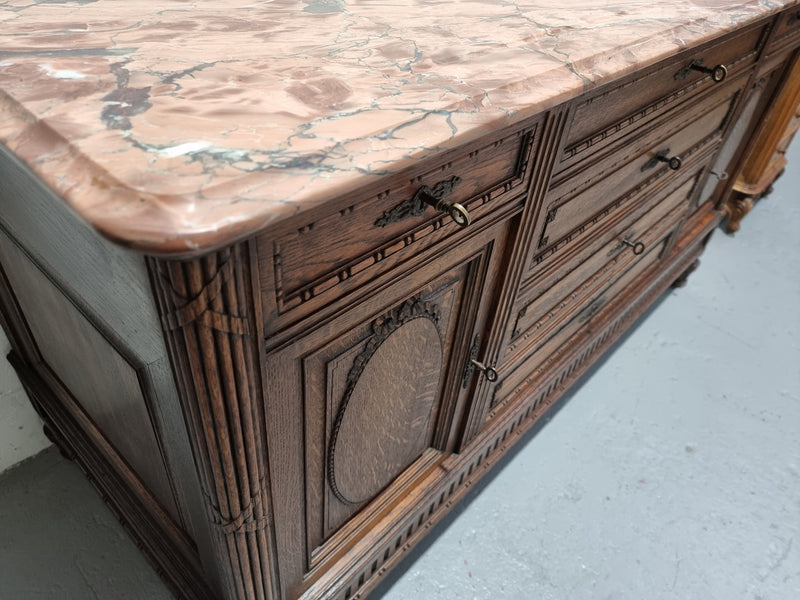 Absolutely beautiful French oak sideboard. It has 6 drawers and 2 cupboards for all your storage needs. There is a lovely coloured marble top and beautiful carving on the doors in good original detailed condition.