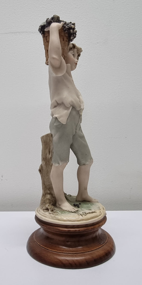 Lovely Italian figurine of boy carrying basket with grapes on a wooden base. It is signed Giuseppe Armani and 1982 FLORENCE. In good original condition.  Please view photos as they form part of the description.