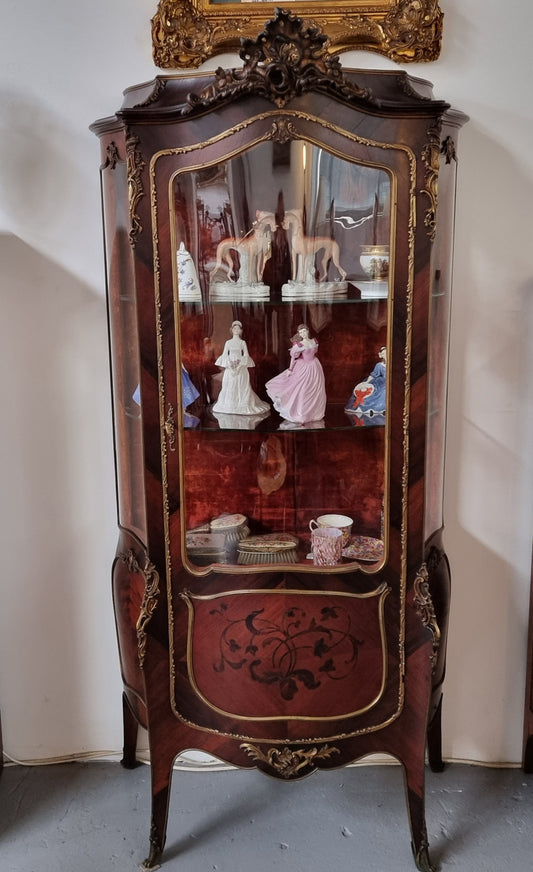 French Louis XV style marquetry inlaid vitrine with ormolu mounts and curved glass. The inside in lined with a red velvet upholstery and has two glass shelves. It has been sourced from France and is in good original detailed condition.
