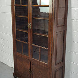 English Walnut two door bookcase with original glass. It has three adjustable shelves and hidden storage below behind two smaller doors. It is in food original condition.