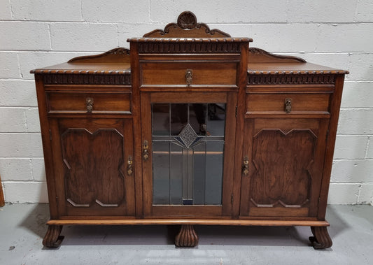 Lovely Oak Tudor style rope edge sideboard with leadlight center door, three drawers and two solid cupboards. In good original condition.