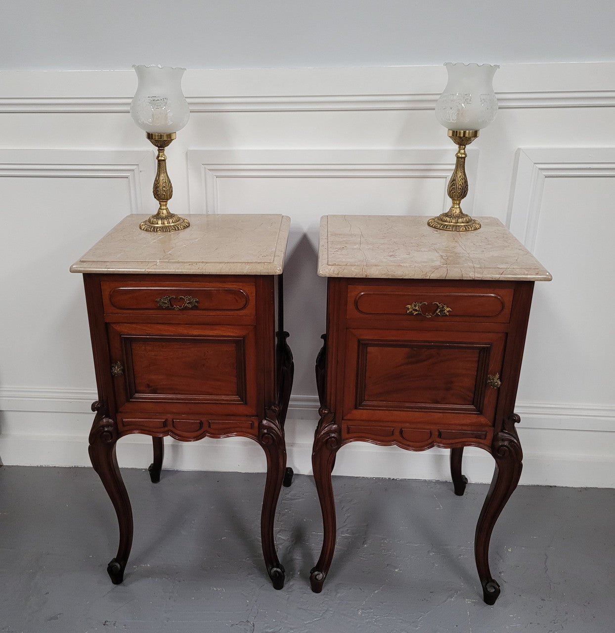 Pair of French Antiloopque Louis XV style Walnut and marble top bedsides. They have lovely carvings along with a drawer and cupboard space. They are in good original detailed condition and have been sourced from France