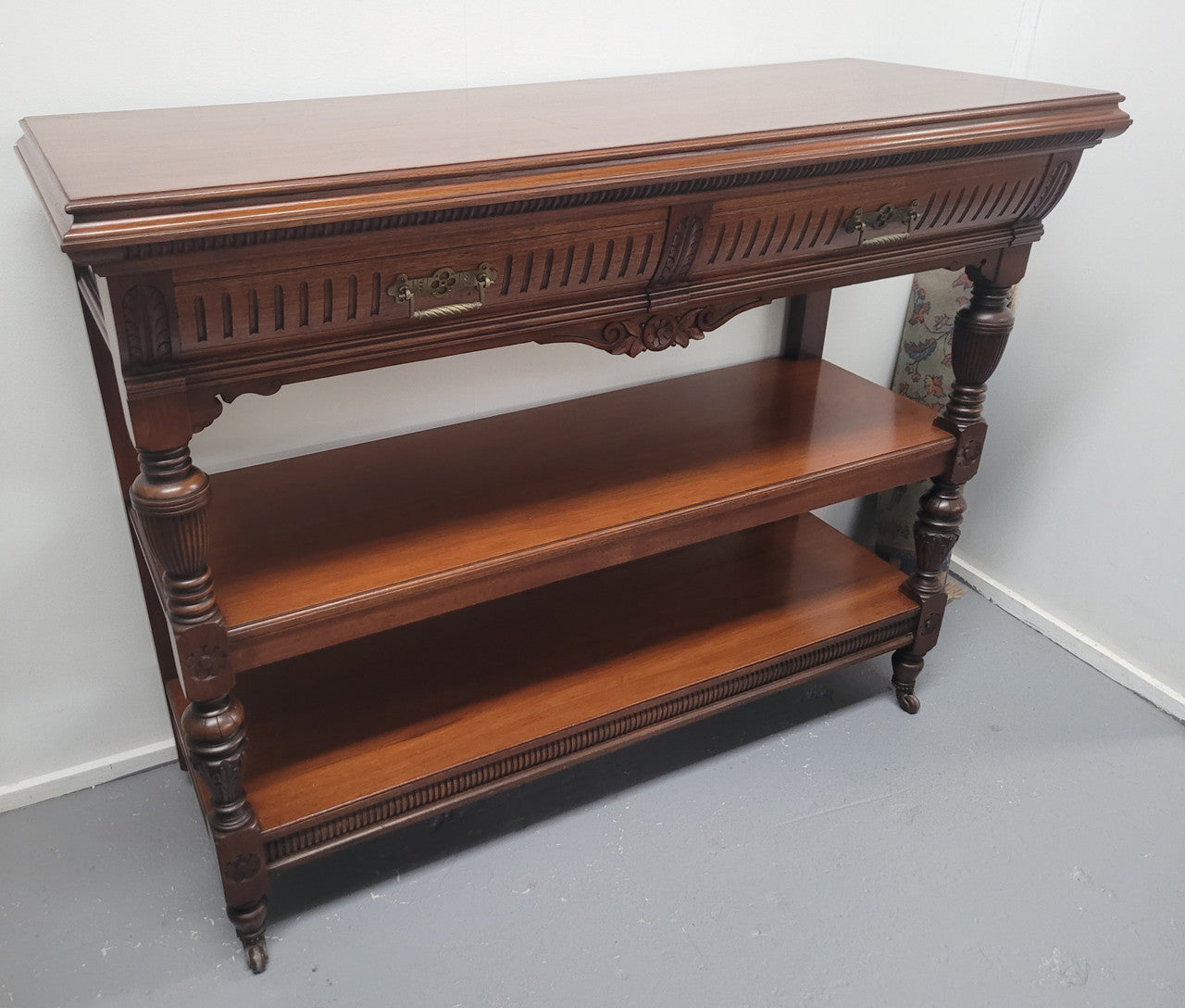 Fabulous quality Edwardian Walnut dumb waiter. It has two drawers and two shelves and is on casters. In good original detailed condition.