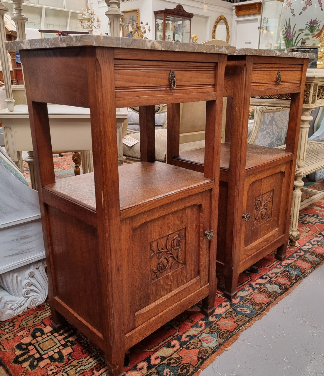 Charming pair of French Oak Arts and Crafts bedsides with shelf, cupboard with carving and marble top.  They have been sourced from France and are in good original detailed condition.