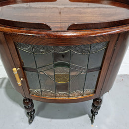 Oak Tudor auto trolley with beautiful leadlight glass. It is on wheels and the door open up to a cabinet with one shelf. In good original detailed condition.
