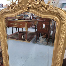 Beautiful French Napoleon III Louis XV style gilt framed bevelled mirror with an ornate crest on top. It has been sourced from France and is in good original detailed condition with the mirror showing signs of age.