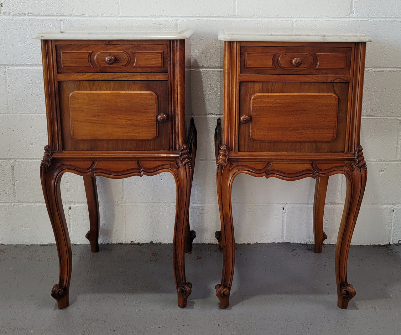 Pair of stunning Louis XV style French Walnut white marble top bedside cabinets. They have one drawer and a cupboard that is marble lined. The marble has been polished and they are in good original detailed condition.