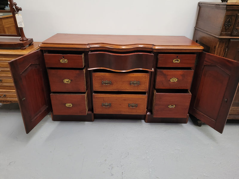 An English Victorian Mahogany sideboard with nine drawers. This amazing piece has loads of storage with three central drawers in the middle and a further six drawers. It has three each side located behind two doors. It has been sourced from locally and in original detailed condition.