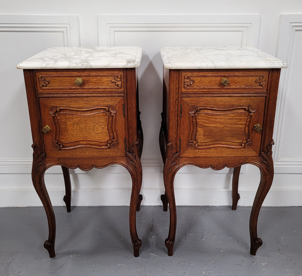 Pair of French Antique Louis XV style Oak marble top night stands. They have beautiful carved cabriole legs and beautiful white marble along with a drawer and cupboard for storage space. They have been sourced from France and are in good original detailed condition.