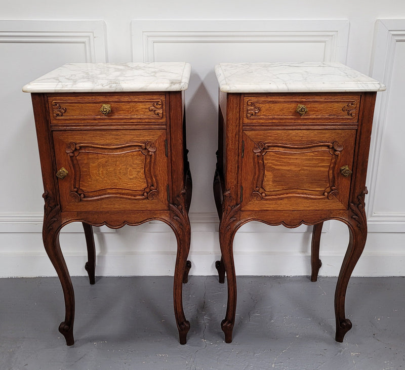 Pair of French Antique Louis XV style Oak marble top night stands. They have beautiful carved cabriole legs and beautiful white marble along with a drawer and cupboard for storage space. They have been sourced from France and are in good original detailed condition.
