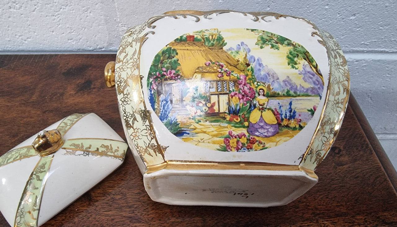 Charming Sadler Biscuit Barrel Decorated With a Thatched Cottage & Lady In Garden