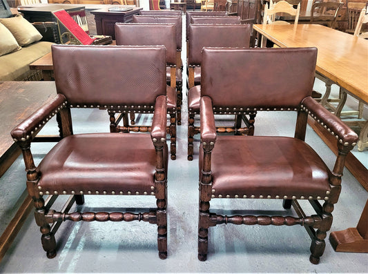 Set of eight Henry II style dining chairs including two carvers. They have leather look upholstery with brass studs. In good original condition.