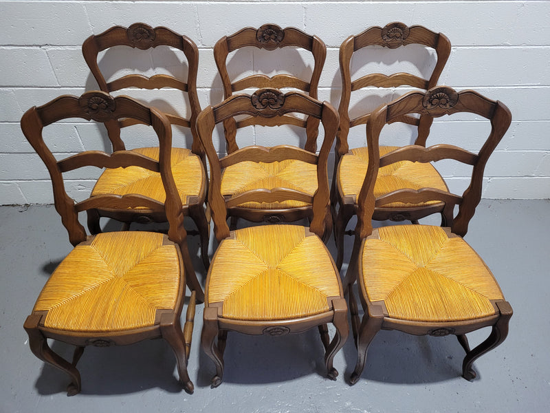 A set of 6 French Louis XV style oak dining chairs with rush seats in good original condition. All chairs have been detailed and re-glued where needed.