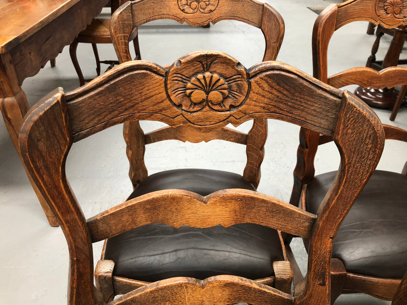 A set of four French Louis XV style, ladder back oak chairs. With finely carved detail and newly upholstered leather look seat. In great original condition. Chairs are comfortable and sturdy for everyday use.