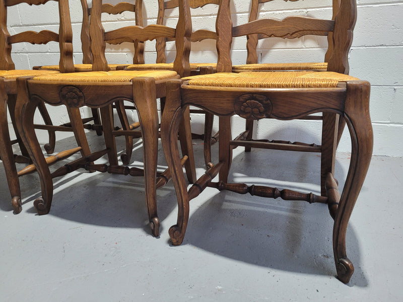 A set of 6 French Louis XV style oak dining chairs with rush seats in good original condition. All chairs have been detailed and re-glued where needed.