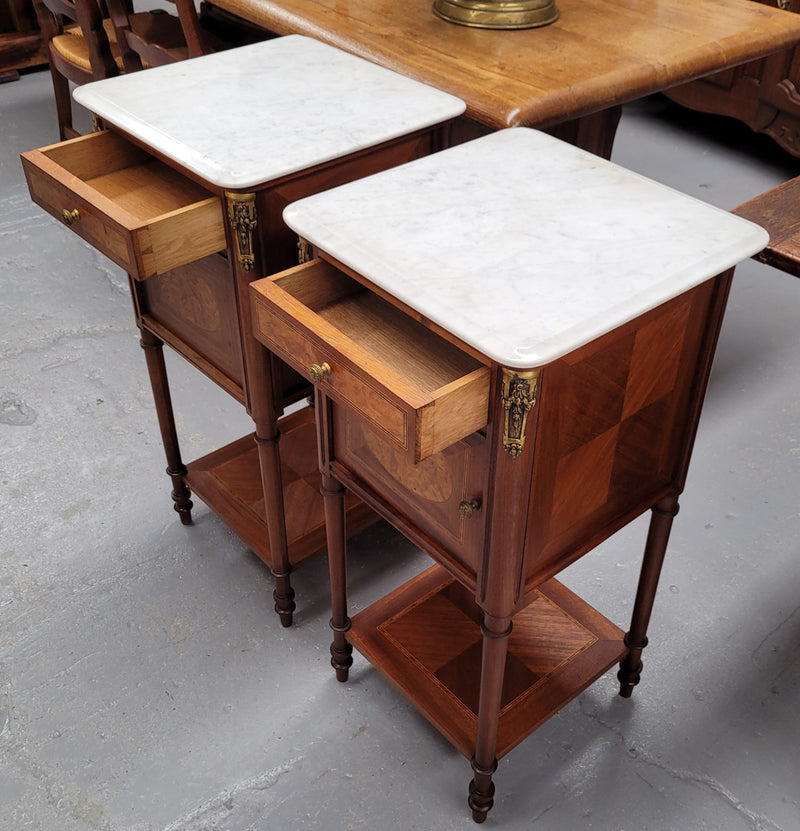 Pair of white marble topped Louis 16th style bedside cabinets consisting of one drawer and one cupboard.  Inlaid with burr walnut and has decorative mounts. They have been sourced from France and are in good original condition.