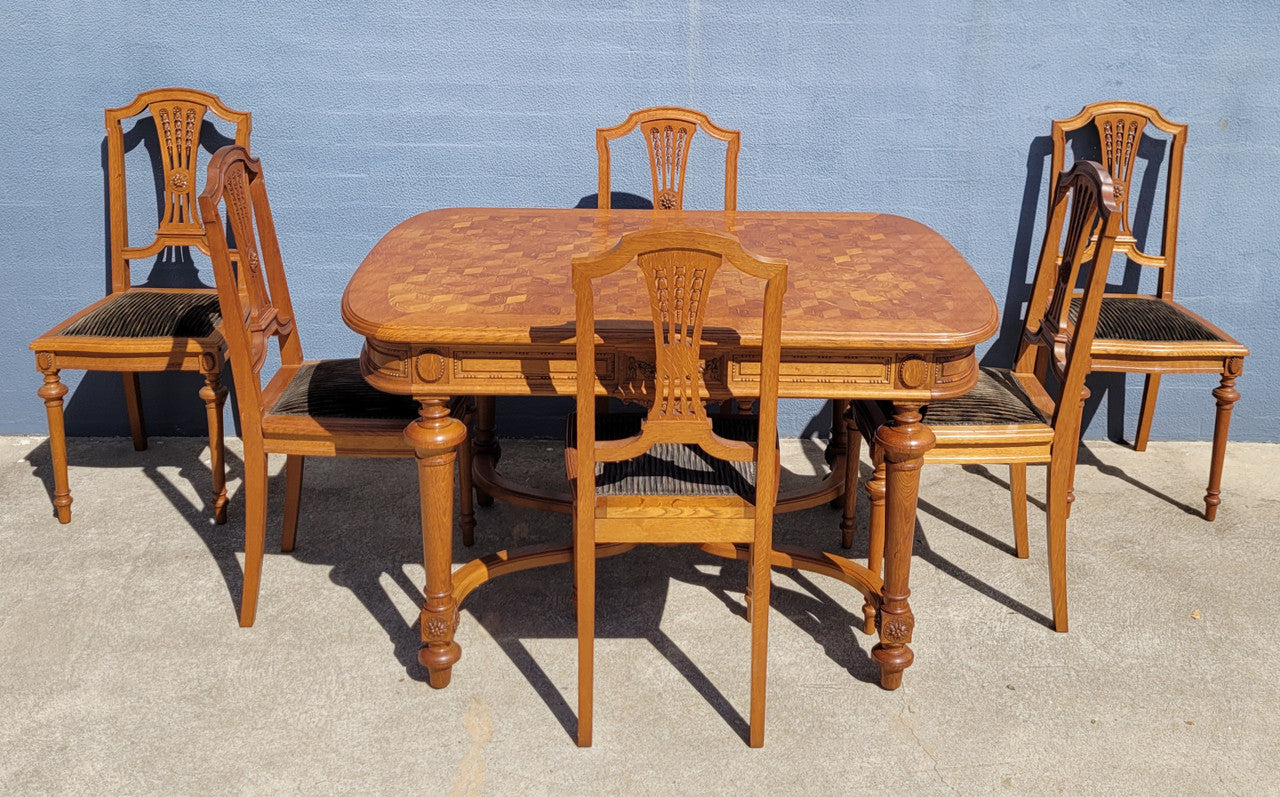 Beautiful carved French Oak dining table with a parquetry top and six matching upholstered chairs. All in good original detailed condition.
