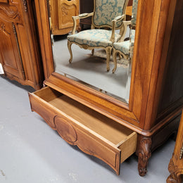 French Louis XV style Walnut armoire with single bevelled mirrored door. It has four adjustable shelves and a hidden exterior drawer at the bottom. It has been sourced from France and is in good original detailed condition.