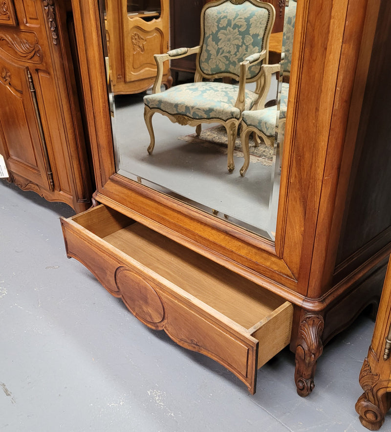 French Louis XV style Walnut armoire with single bevelled mirrored door. It has four adjustable shelves and a hidden exterior drawer at the bottom. It has been sourced from France and is in good original detailed condition.