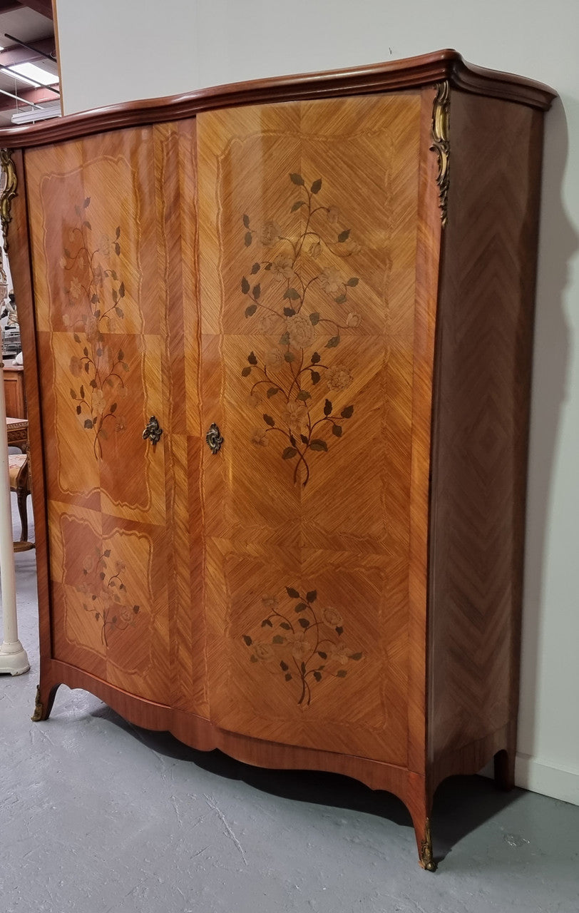 Tall French Marquetry inlaid armoire / bookcase with ormolu mounts. The interior has six fully adjustable shelves and two drawers. It is in good original detailed condition.