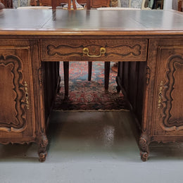 Fabulous Louis XV style French Oak beautifully carved full partners desk with an amazing tooled leather top. Both sides have a functioning drawer in the middle and two cupboards either side. On both sides one cupboard door opens up to four smaller internal drawers. Plenty of storage space and a large top surface to work on. It is in good original detailed condition.