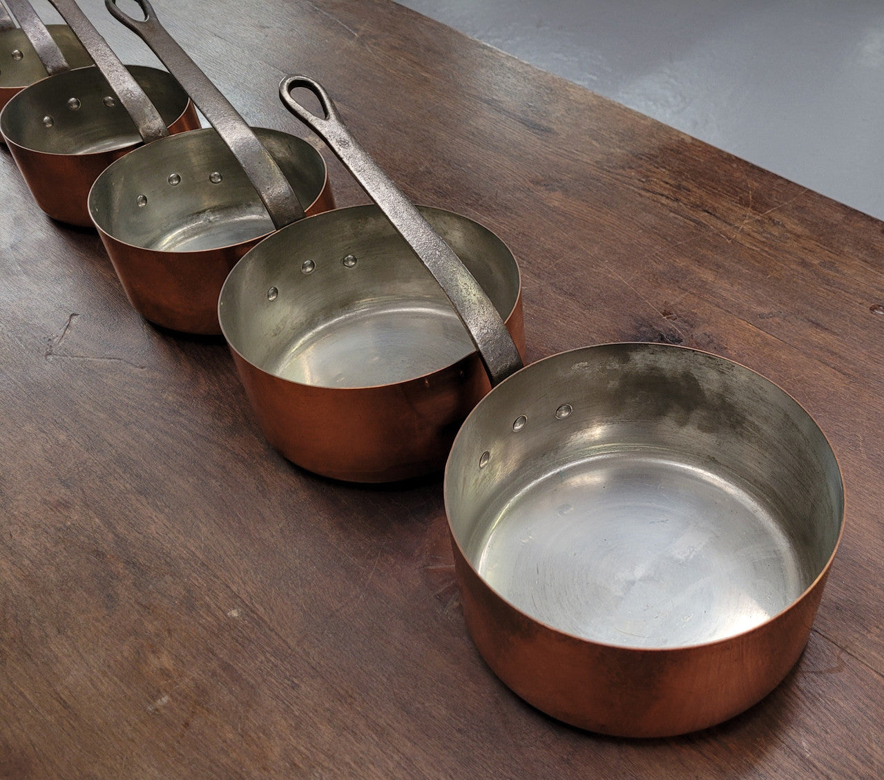 Set of five copper sauce pans with foundry stamp. They have been sourced from France and are in good original detailed condition.