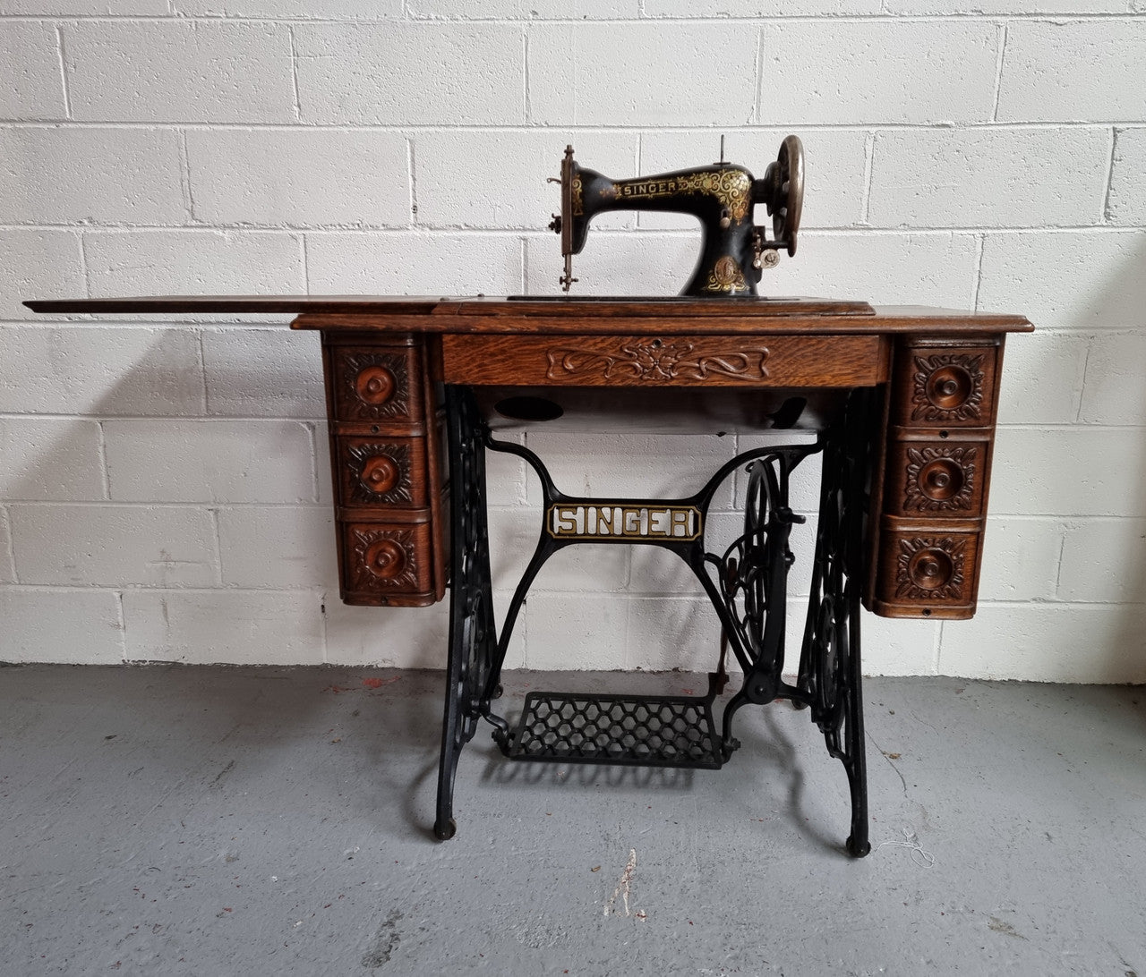 Singer Treadle sewing machine with six decorative side drawers and one centre drawer in Oak on cast iron base. It is in original condition.