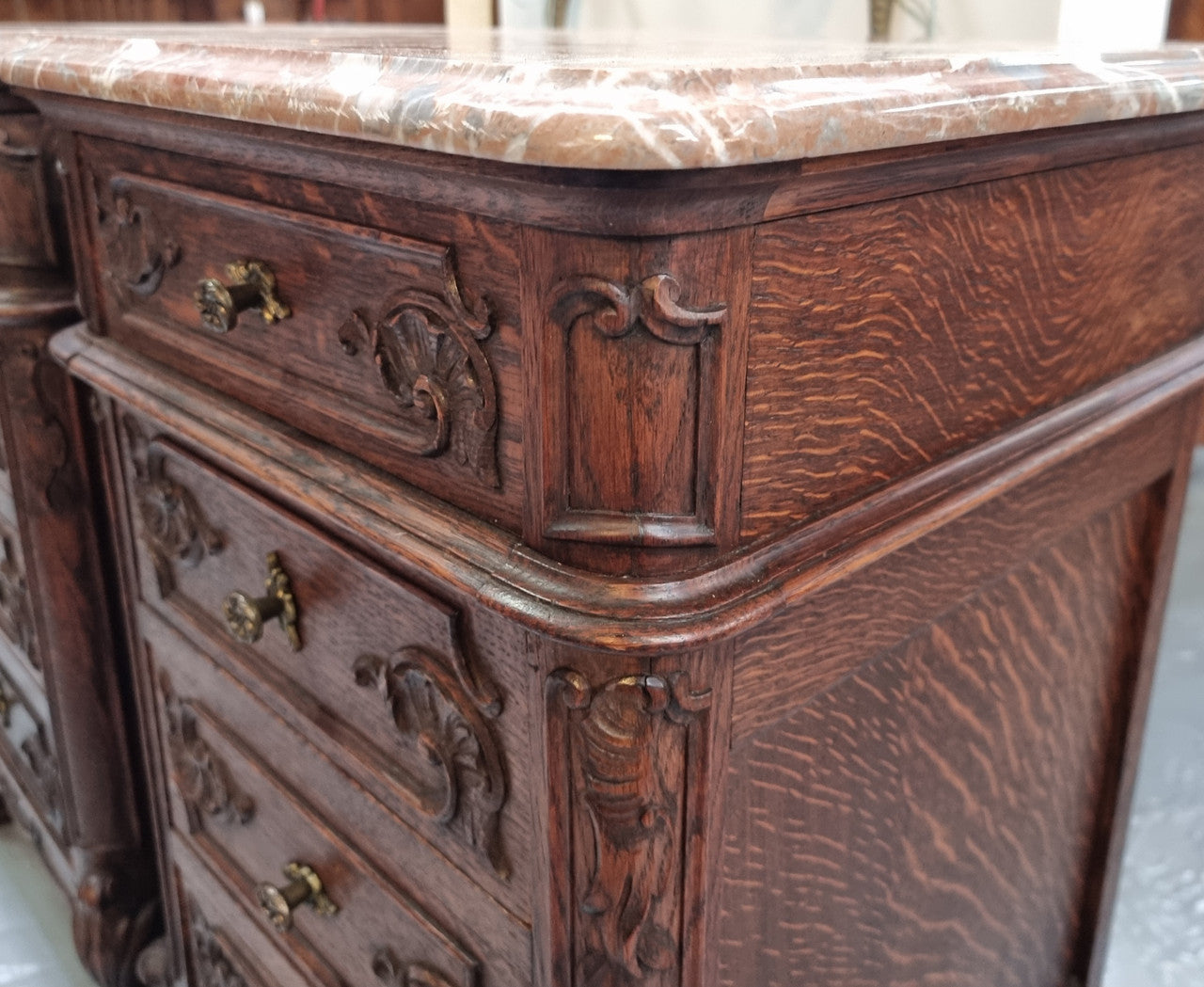 A pair of hard to find French Oak Louis XV style four drawer marble topped bedsides with attractive carvings. They are in good original detailed condition and have been sourced from France.