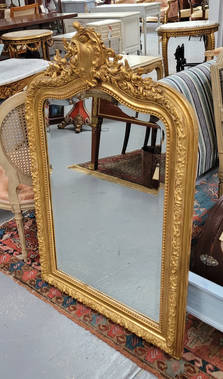 Beautiful French Napoleon III Louis XV style gilt framed bevelled mirror with an ornate crest on top. It has been sourced from France and is in good original detailed condition with the mirror showing signs of age.