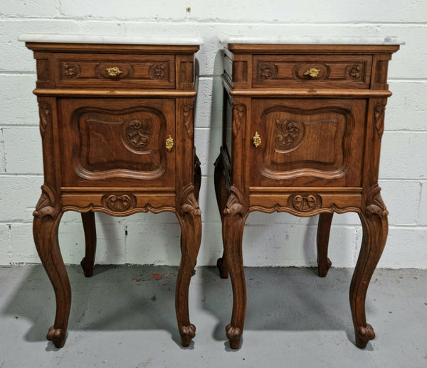 Lovely pair of French Oak carved Louis XV style bedside cabinets with a white marble top, drawer and cupboard in good original detailed condition.