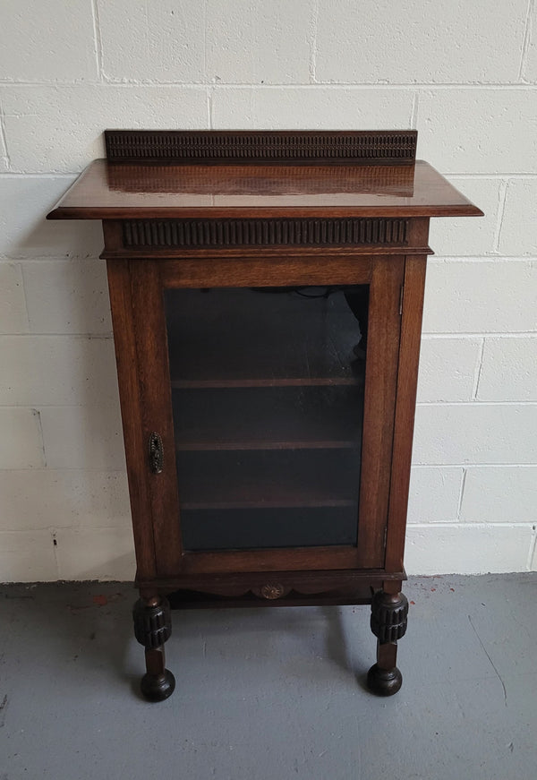 A very practical compact Oak Tudor style display cabinet with three fixed shelves. In good original detailed condition.