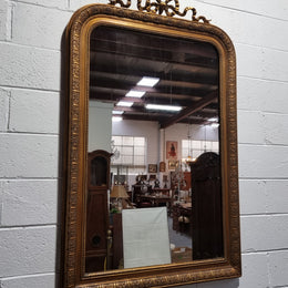 Late 19th century French gilt mirror with beautiful ribbon crest on top. In good original detailed condition.