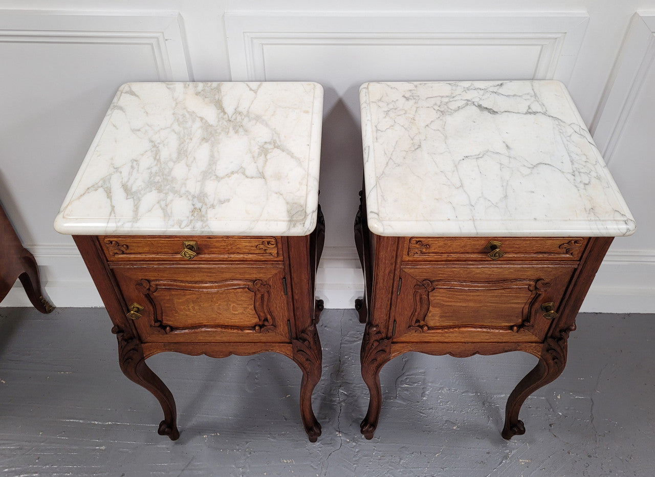 Pair of French Antique Louis XV style Oak marble top night stands. They have beautiful carved cabriole legs and beautiful white marble along with a drawer and cupboard for storage space. They have been sourced from France and are in good original detailed condition.