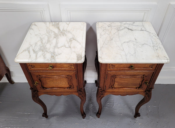 Pair of French Antique Louis XV style Oak marble top night stands. They have beautiful carved cabriole legs and beautiful white marble along with a drawer and cupboard for storage space. They have been sourced from France and are in good original detailed condition.