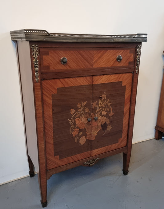 Louis 16th style marquetry inlaid side cabinet with a pierced brass gallery surrounding a marble top. It has two doors open up to storage with one shelf and a drawer above that. In good original detailed condition.