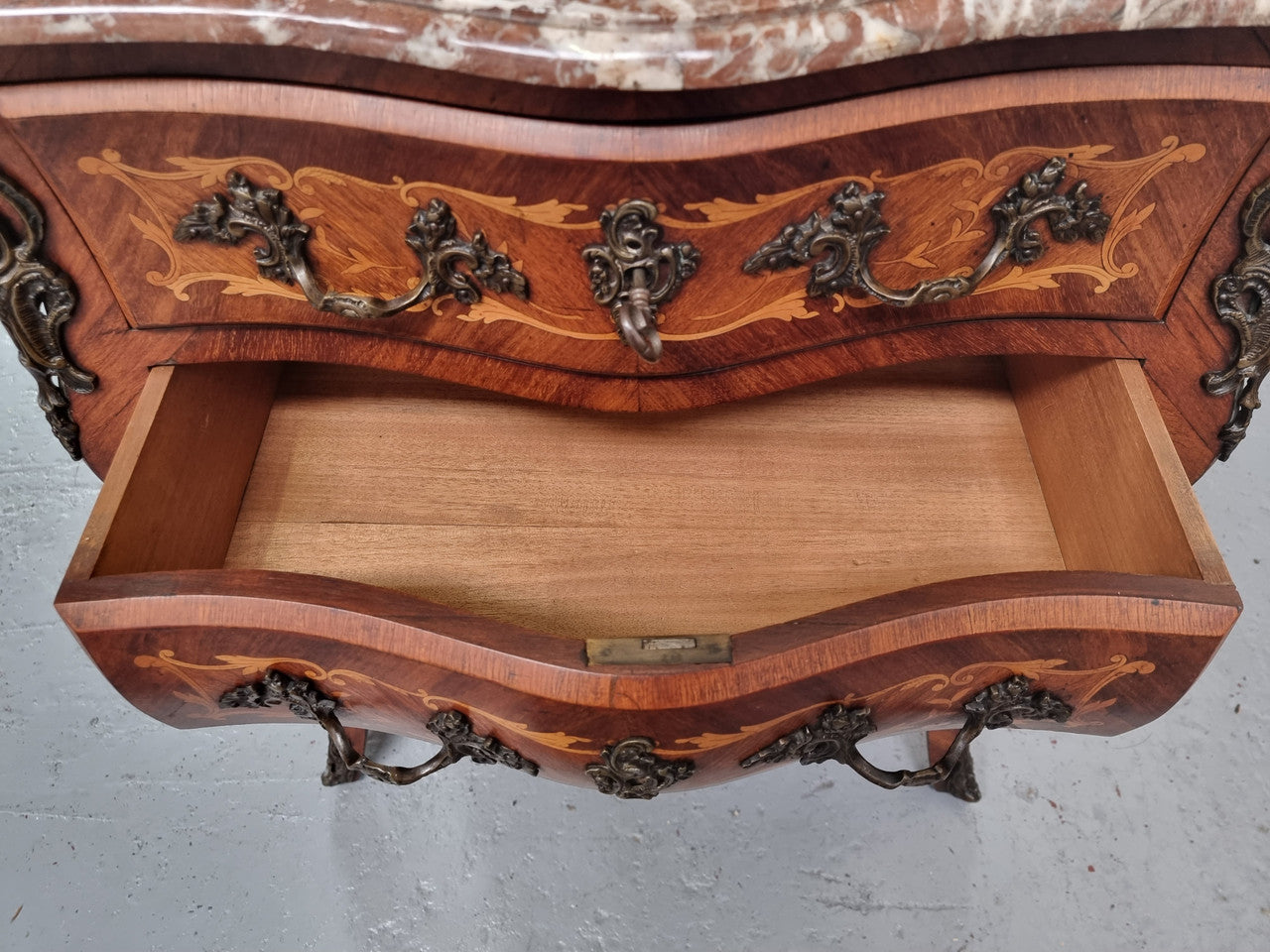 Antique French Louis XV style compact three drawer marble top commode with marquetry inlay and ormolu mounts. Sourced from France and in good original detailed condition.