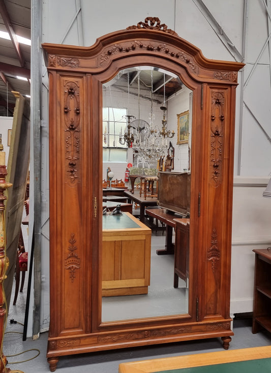 Imposing Louis XV style single mirrored door Walnut armoire. Features deep carved decoration, two interior drawers and three adjustable shelves. It is in good original detailed condition and has been sourced from France.