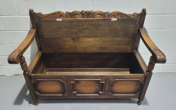 English Oak Tudor style hall seat with lift up top and a storage compartment underneath. It is in good original detailed condition with its original finish.