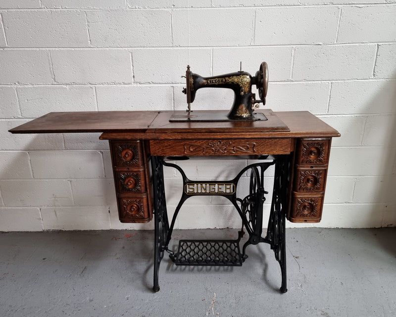 Singer Treadle sewing machine with six decorative side drawers and one centre drawer in Oak on cast iron base. It is in original condition.