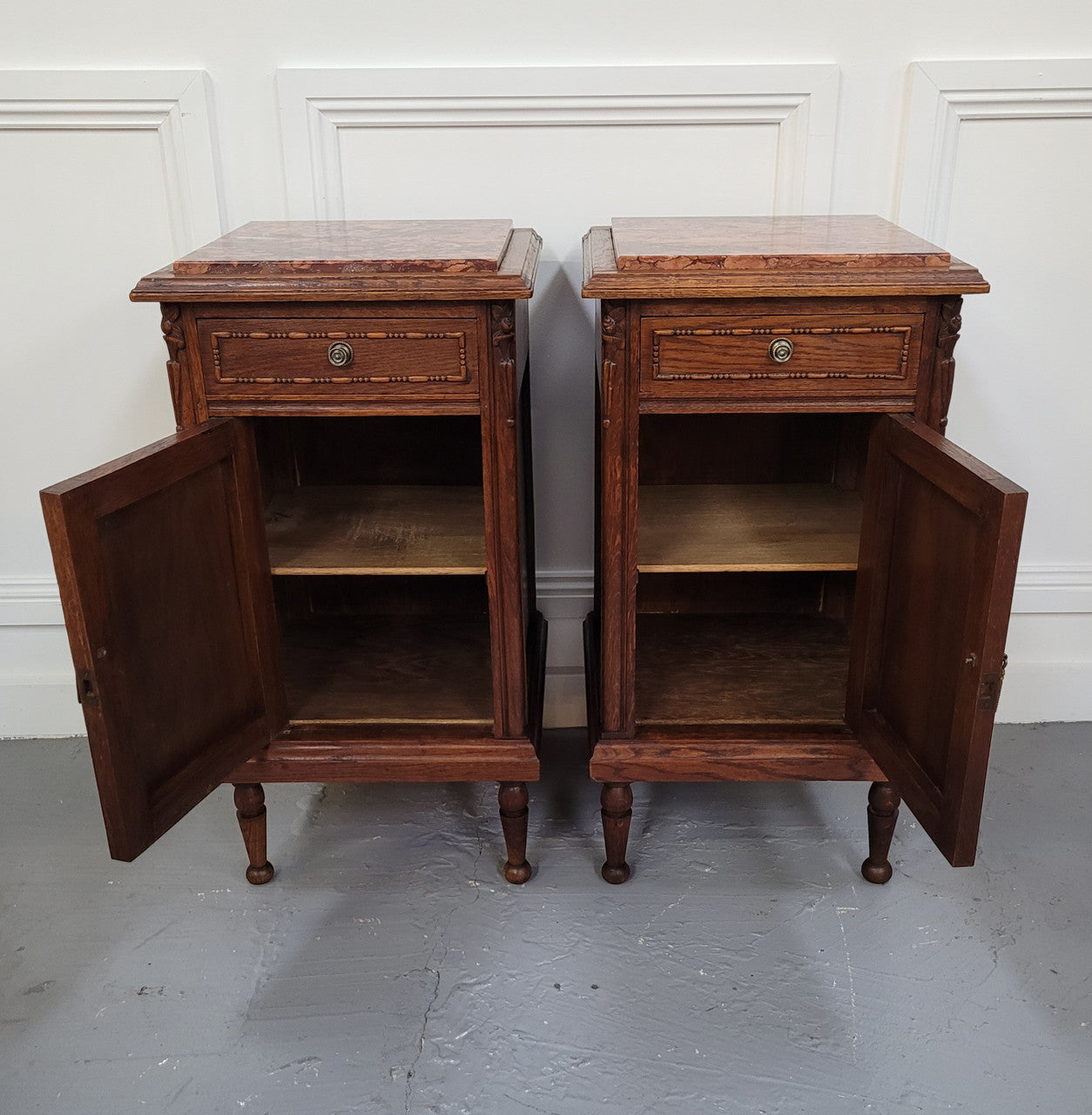 Pair of French Art Deco Oak and rouge inset marble top bedside cabinets. They have one drawer and one cupboard with elegant carving on the door. They have been sourced from France and are in good original detailed condition.