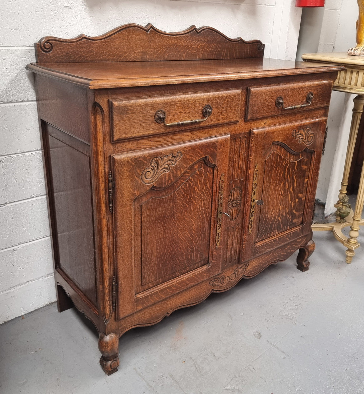 French Louis XV style Oak two door, two drawer sideboard. It is of pleasing narrow proportions and has one interior shelf. It has been sourced from France and it is in good original detailed condition.
