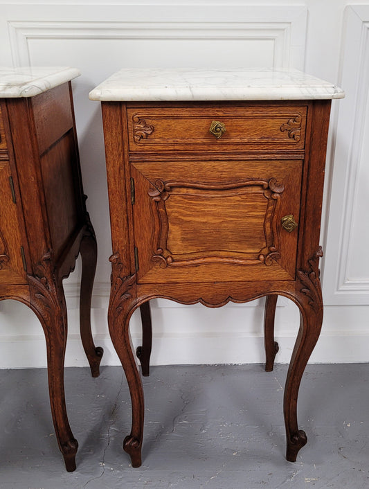 Pair of French Antique Louis XV style Oak marble top night stands. They have beautiful carved cabriole legs and beautiful white marble along with a drawer and cupboard for storage space. They have been sourced from France and are in good original detailed condition.