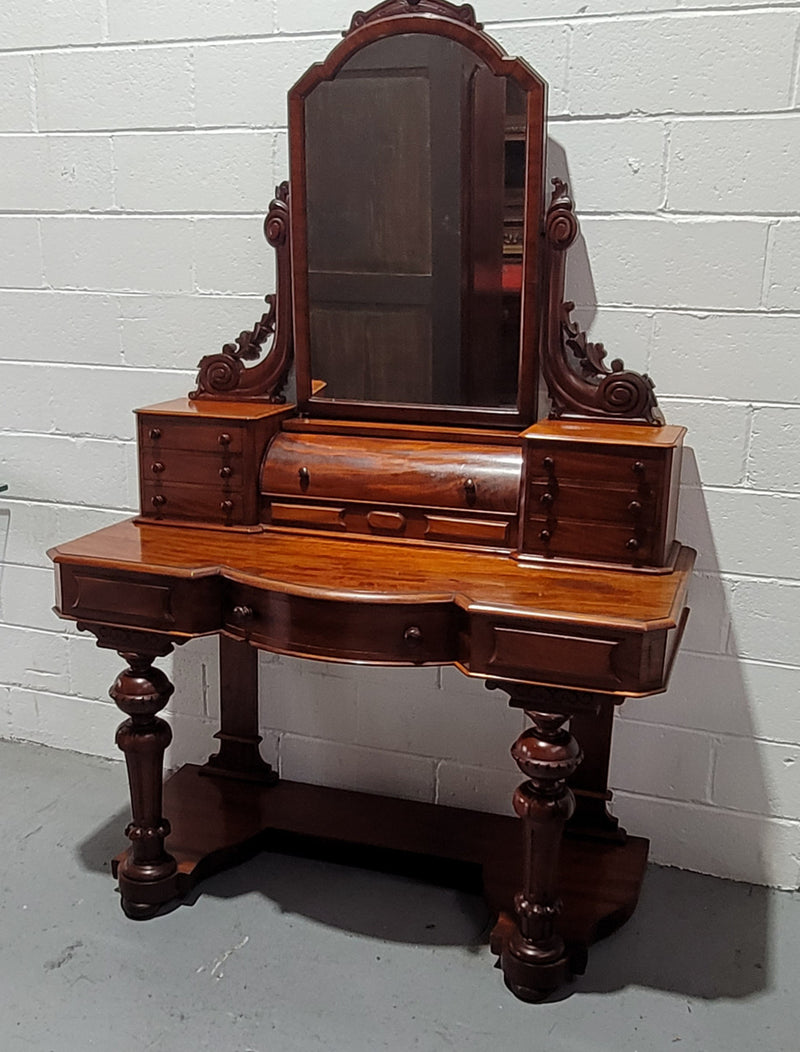 Beautiful Flame Mahogany Victorian duchess dressing table. Circa 1880 in date. It has a serpentine front outline and has an adjustable swing frame mirror. It is fitted with a central roll up storage section and then has three small drawers to either side, aswell as a central drawer in the middle of the serpentine front. It is in good original condition.