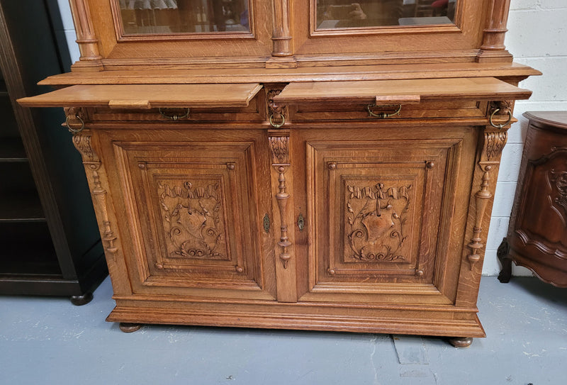 Amazing French 19th Century Oak two-door bookcase. Amazing detailed carvings throughout and plenty of storage space with three adjustable shelves at the top, two drawers, and a further shelf at the bottom. Also has two pull out reading slides giving you a large area to view your books on. In very good original detailed condition.