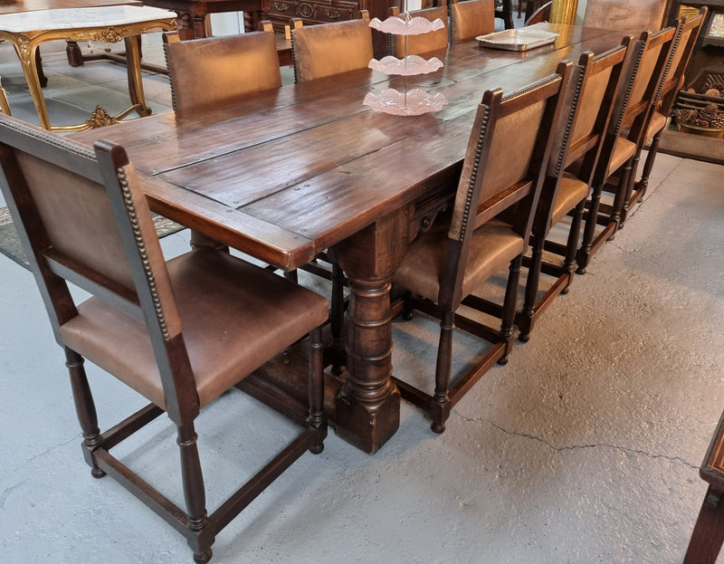 Amazing three meter long dark Oak Farmhouse dining table with a pedestal base. Comes with matched set of 10 very comfortable leathered chairs. All is in very good original detailed condition.