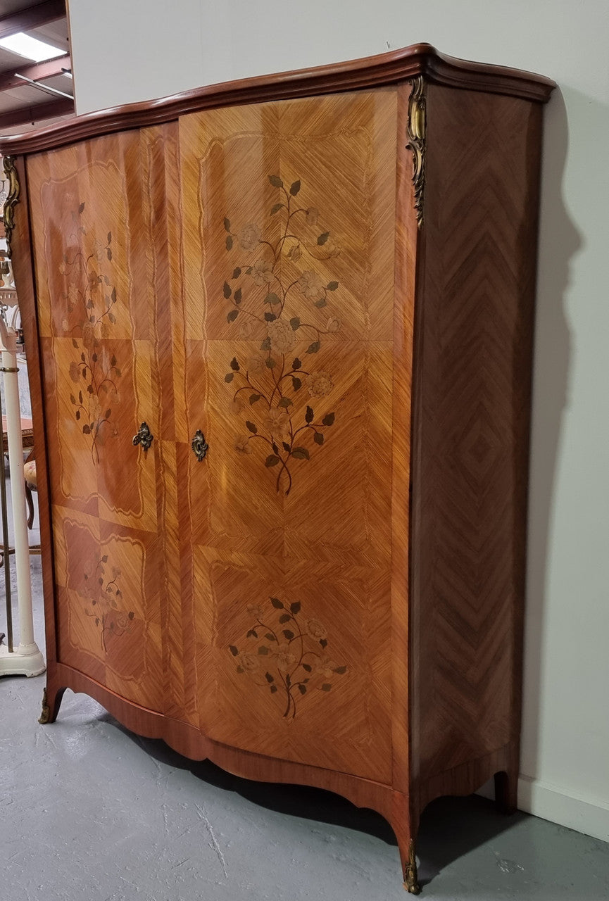 Tall French Marquetry inlaid armoire / bookcase with ormolu mounts. The interior has six fully adjustable shelves and two drawers. It is in good original detailed condition.